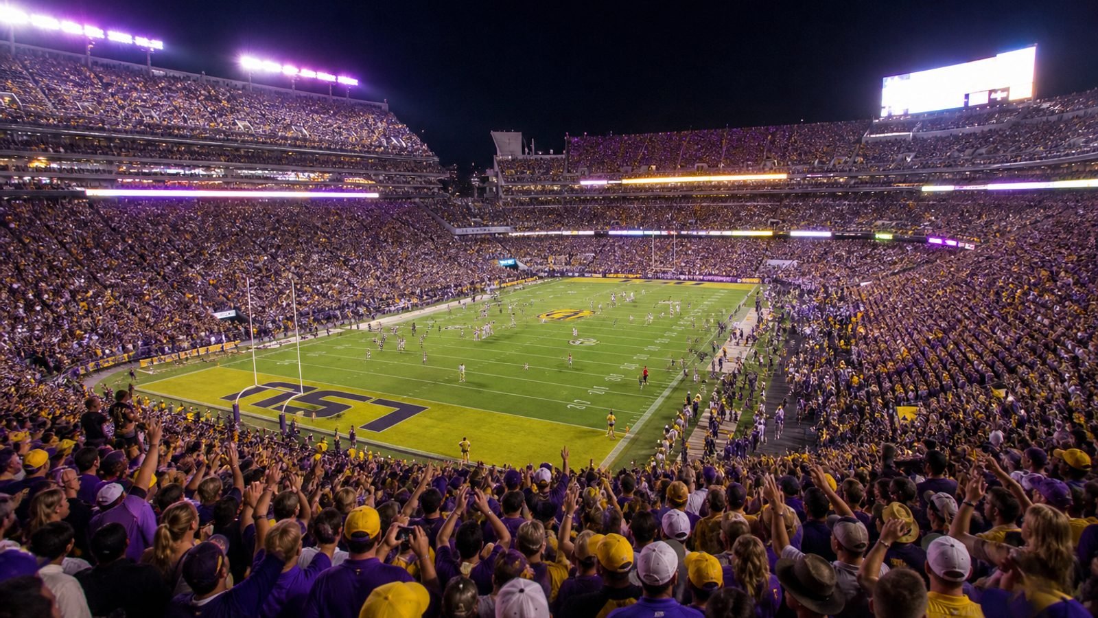 A packed college football stadium at night under the lights