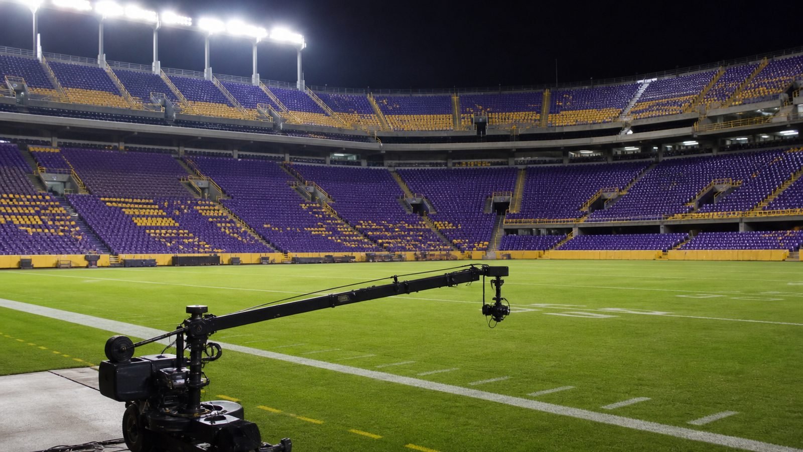 Empty college football stadium seats under night lights