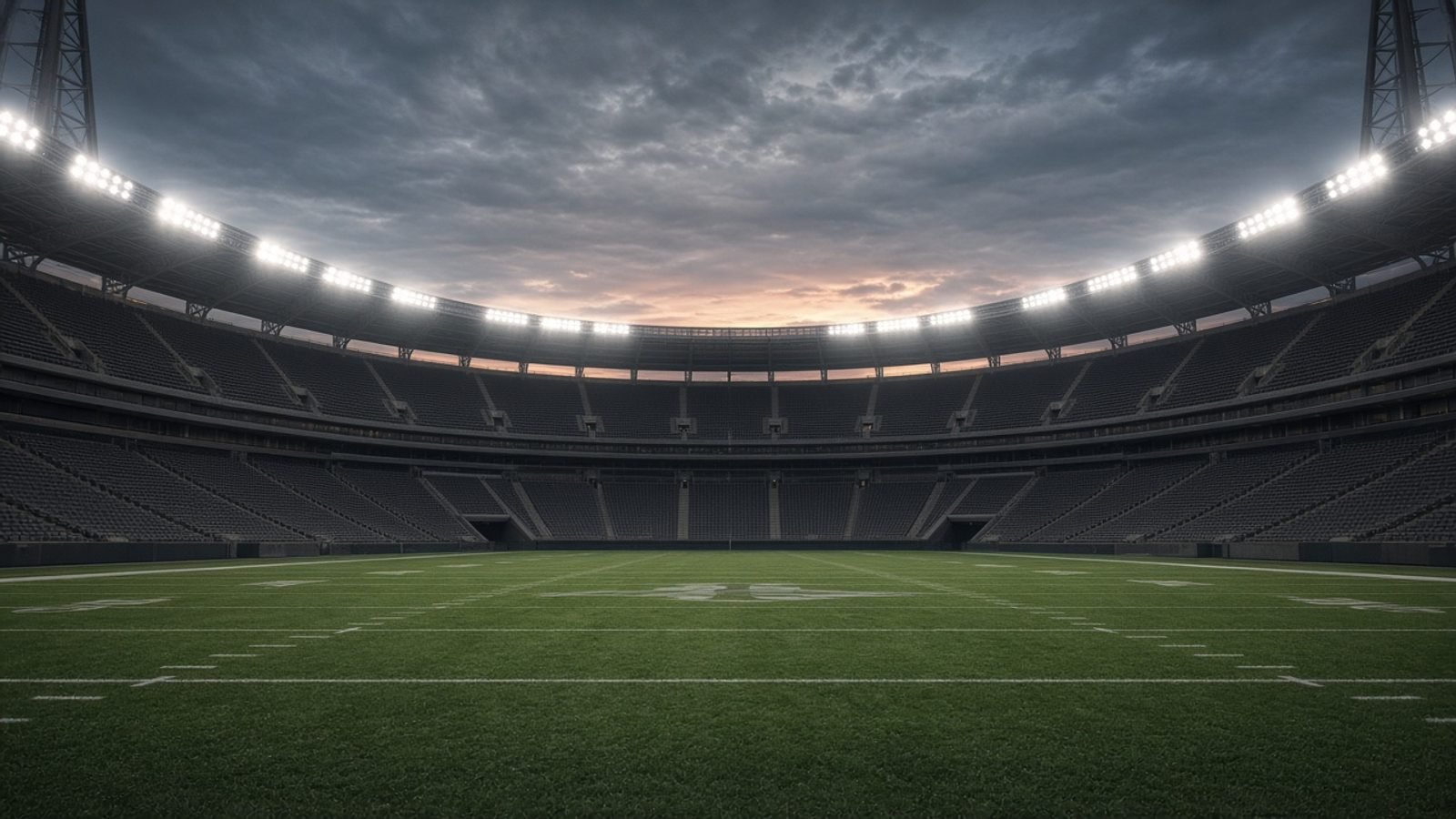 An NFL stadium at twilight with floodlights over an empty field