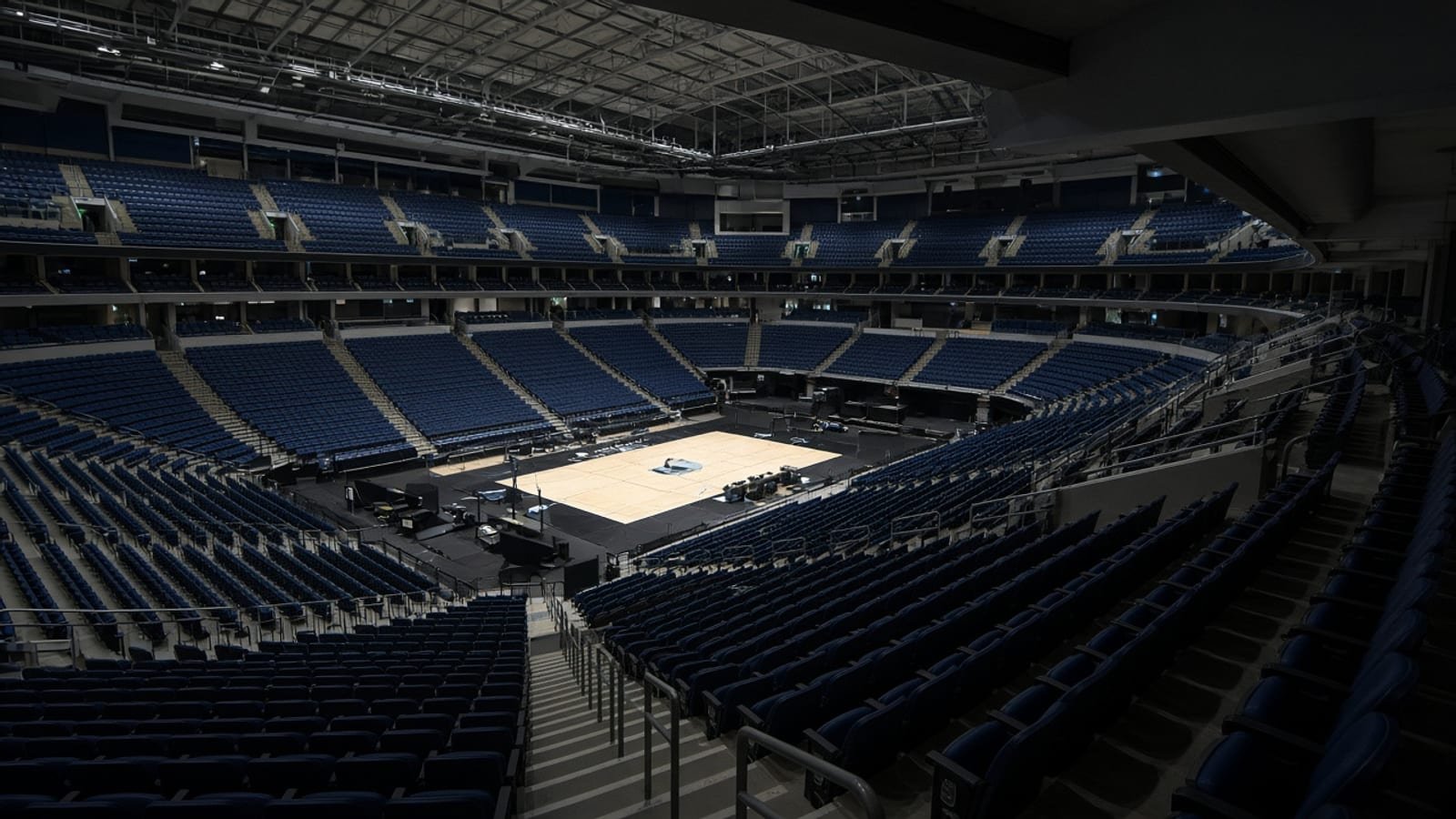 An indoor arena with empty upper-deck seats and a lit floor