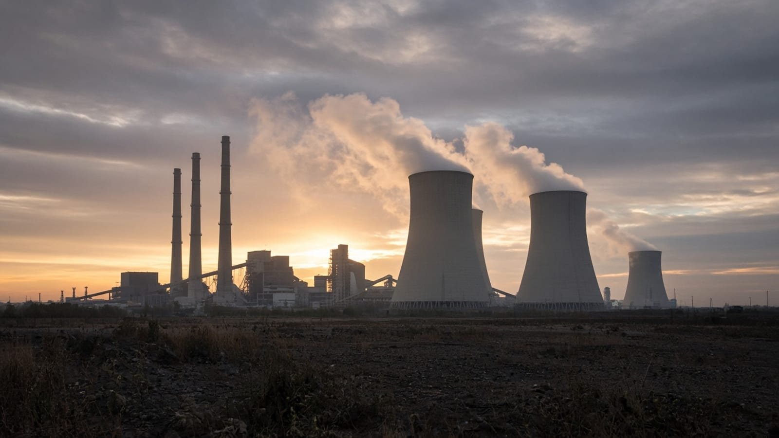 A coal-fired power plant with cooling towers at dawn