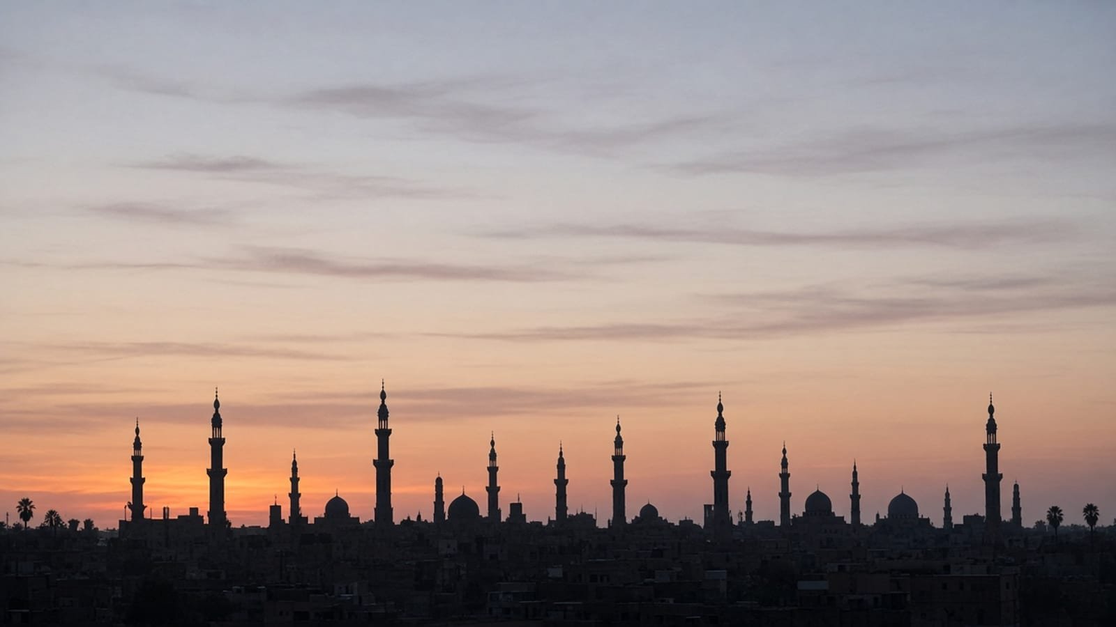 A desert city skyline at dusk with minarets in silhouette