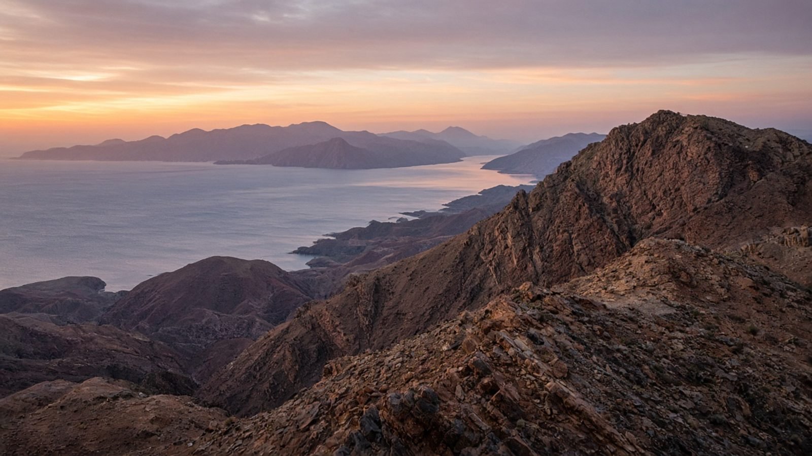 Rugged desert mountains at dusk overlooking a distant sea strait