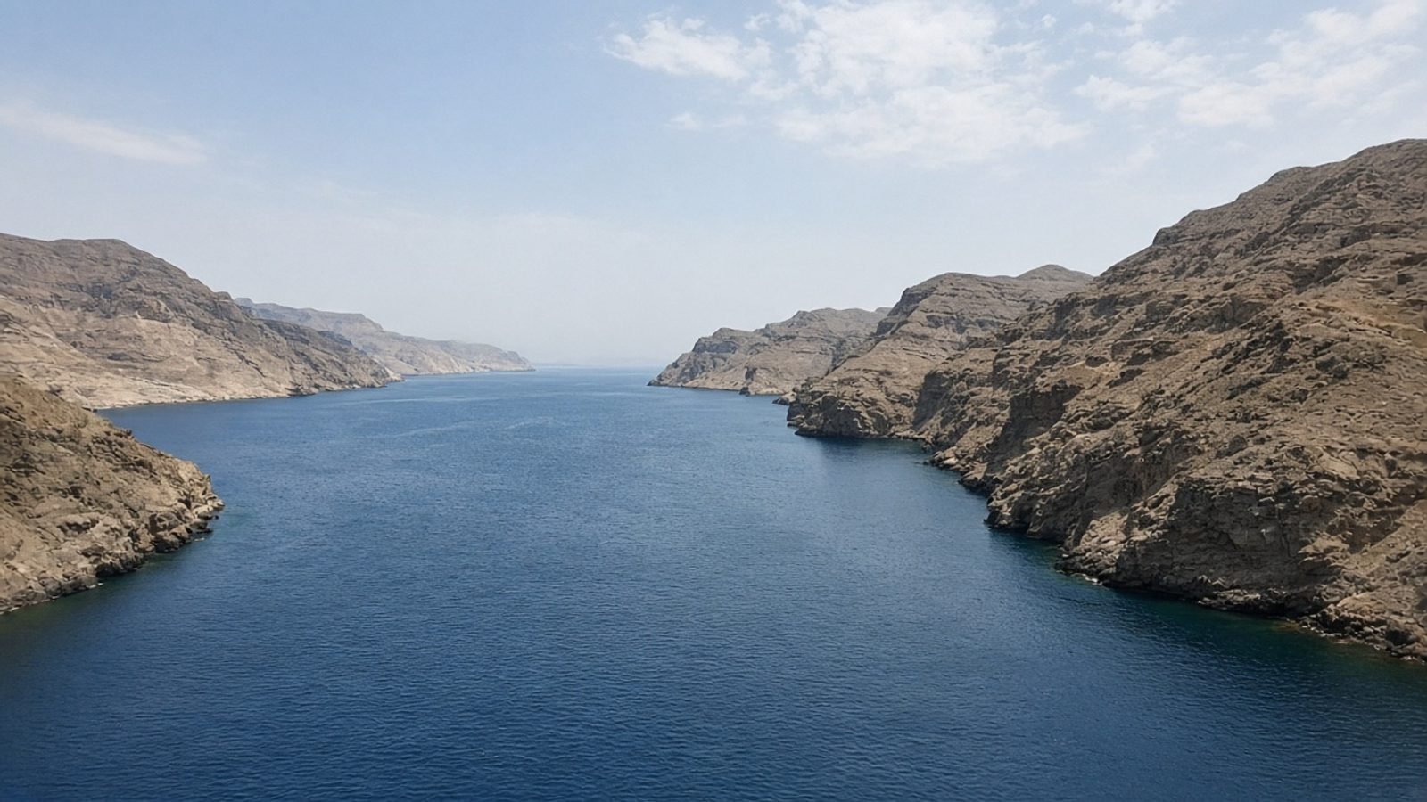 A narrow gulf strait at midday with empty water and arid cliffs