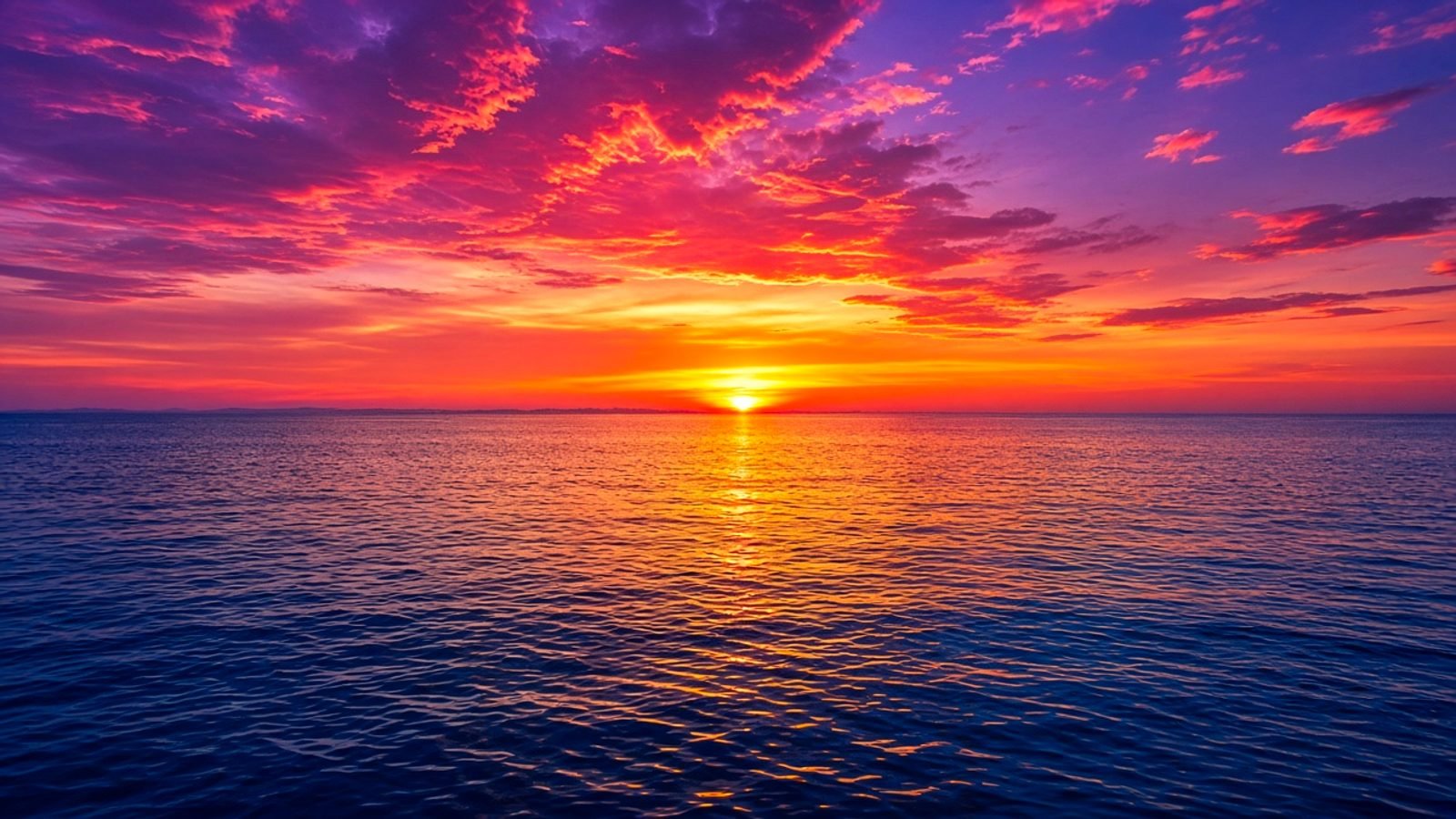 An orange and magenta sunset over deep cobalt sea
