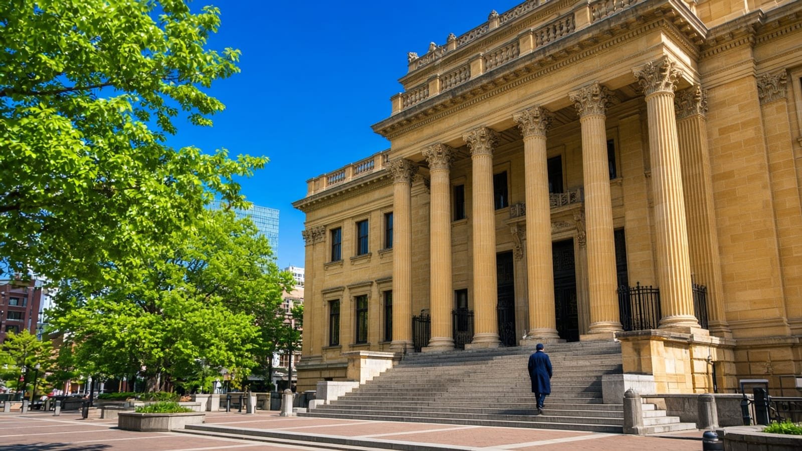 A gold New York courthouse under a cobalt sky with green trees